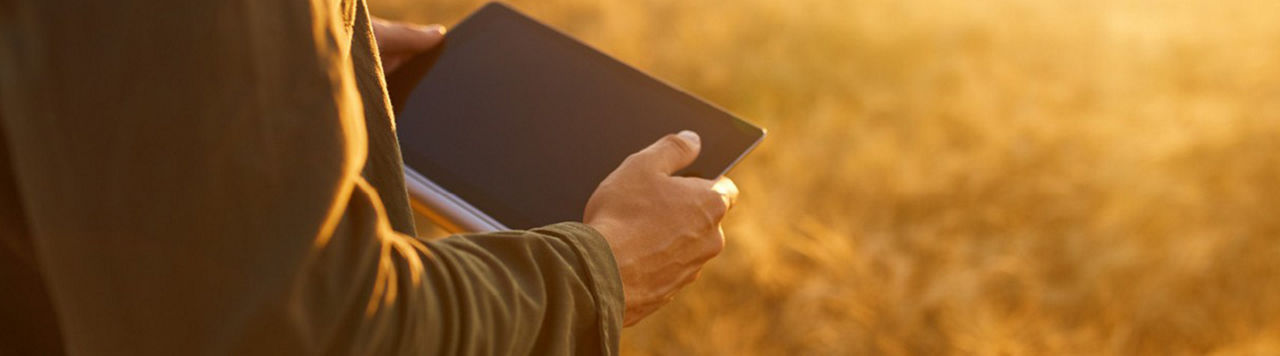 A person holding a tablet in a field