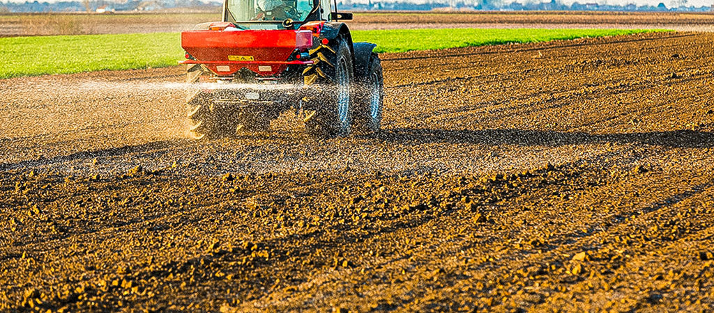 Trator espalhando fertilizantes na lavoura