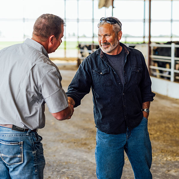 Farmer and rep shaking hands in a barn